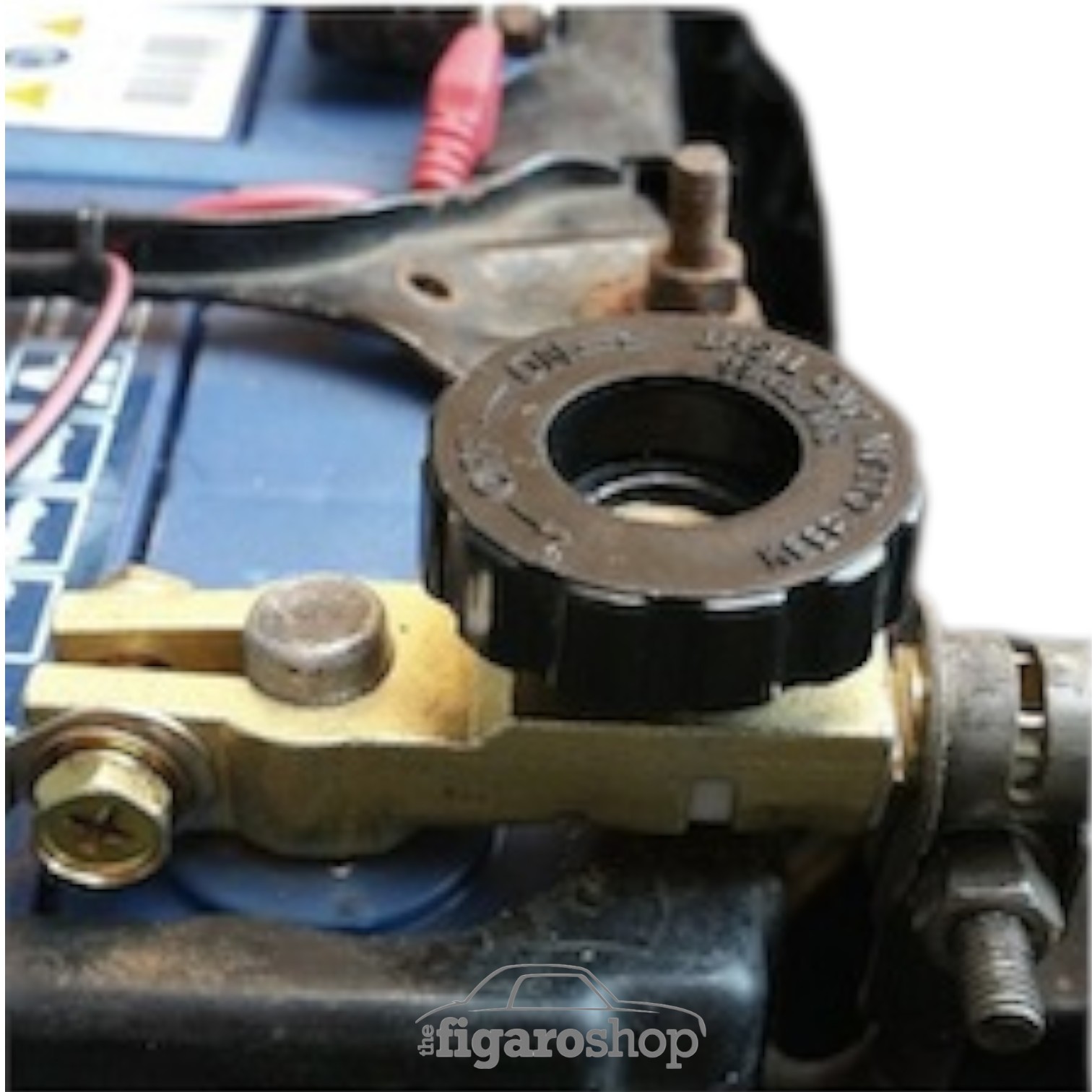 Battery Isolator In Brass Colour Fitted In Nissan Figaro Showing Black Turn Wheel and Battery Terminal